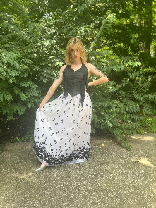 Angled view on the model holding out one side of the skirt, showing the black floral flocking