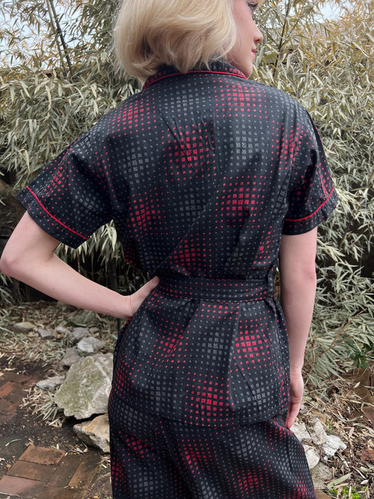 Back view of the pajama top on the model showing the red-piped collar and sleeve cuffs and the belt at the waist