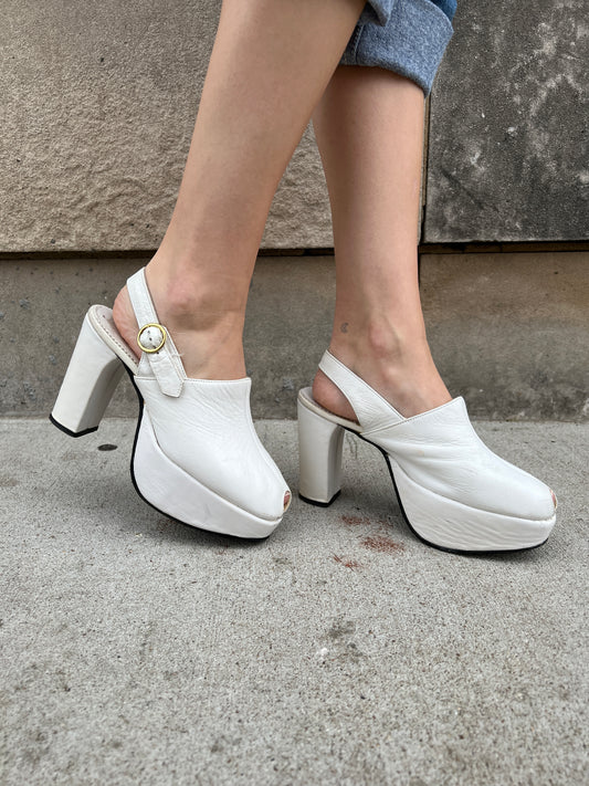 Opposite side view of both shoes on the model showing the buckle straps, peep toes and thick platforms