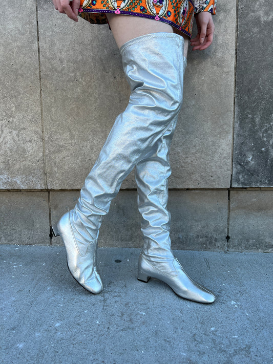 Side view on the model with one foot lifted, showing the boots reaching the upper thigh and the low heels