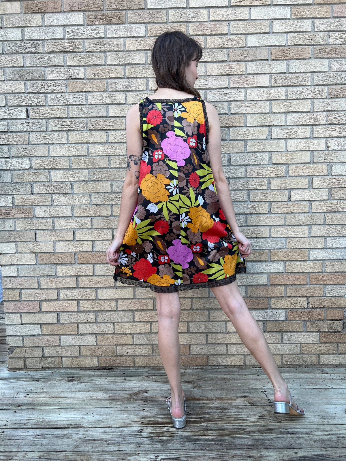 Back view on the model with the head turned, showing the floral print and black lace trim