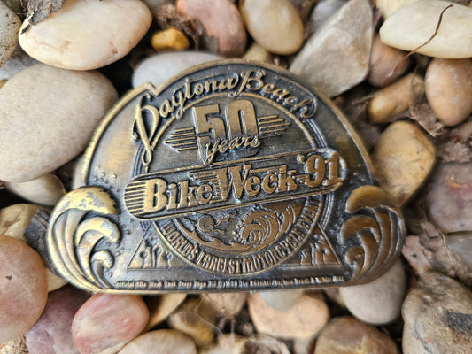 Belt buckle reading Daytona Beach 50 years Bike Week '91, on pebbles