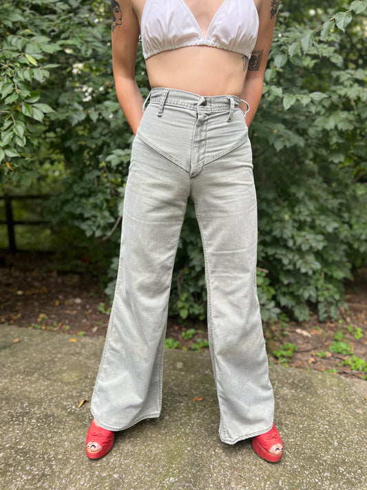 Front view of high-waisted slate green bell bottom jeans with a waist button, worn by a model