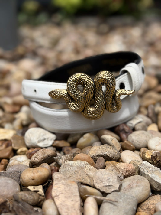 White leather belt coiled on pebbles, with a buckle shaped like a curled up snake