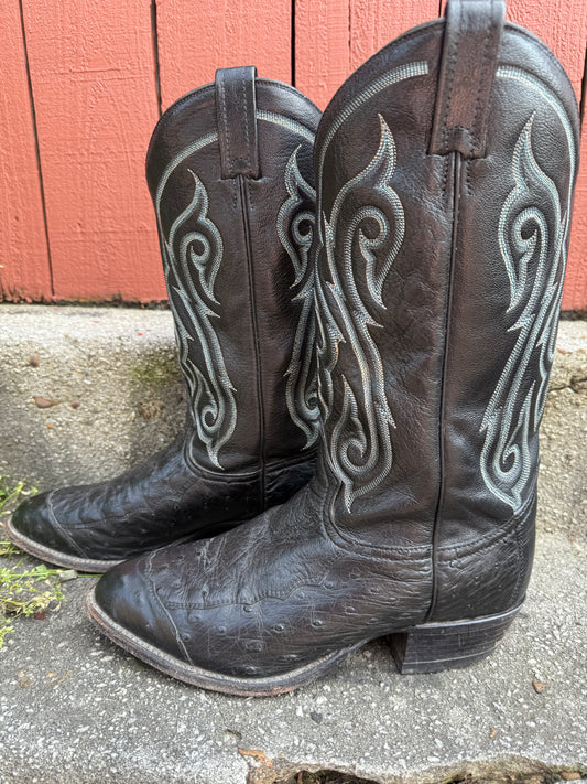 Pair of black ostrich leather cowboy boots with white and blue stitching on the shafts, shown side by side on a step