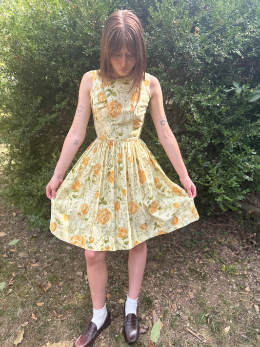 Gold floral cotton sundress with a sleeveless bodice and full skirt, worn by a model