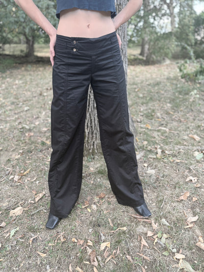 Front view on the model of black wide leg low rise pants with a wide two-button waistband, standing with feet apart