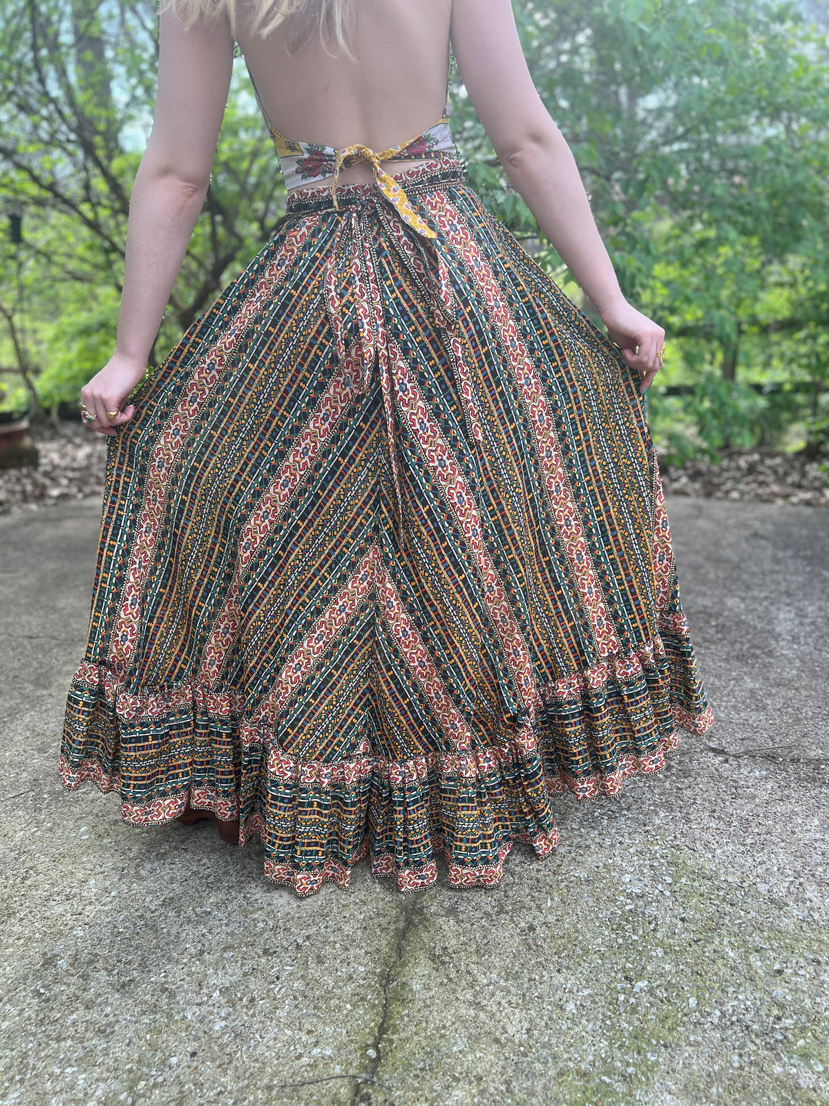 Back view on the model showing the self tie belt at the waist, print panels and ruffled hem