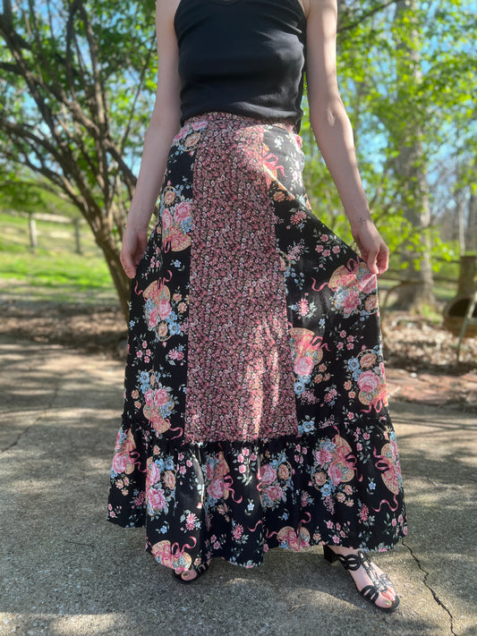 Black prairie maxi skirt with pink, blue and green floral panels and a ruffled hem, worn by a model