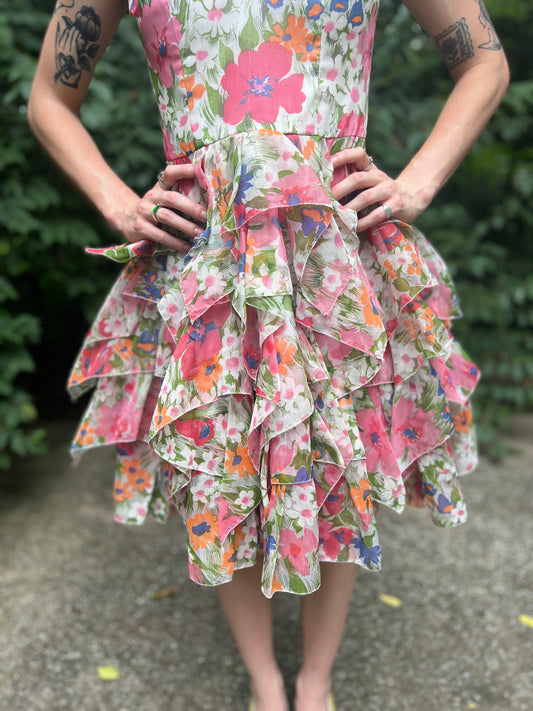 Close-up of the waist and tiered skirt of the pink and white floral dress, on a model
