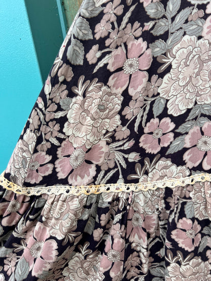 Close-up of the floral print and crocheted trim above the gathered ruffle, held up against a wall
