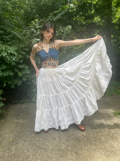 Model holding out one side of the full skirt to show its width and the tiered, eyelet-trimmed hem