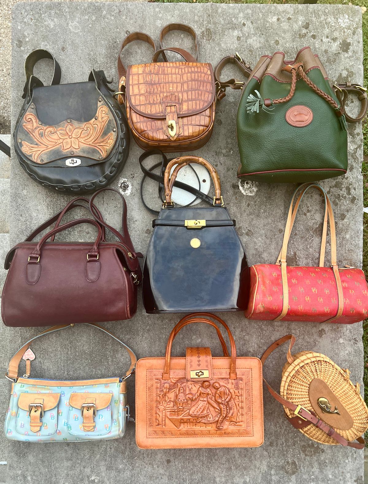 Nine handbags laid out on a stone surface