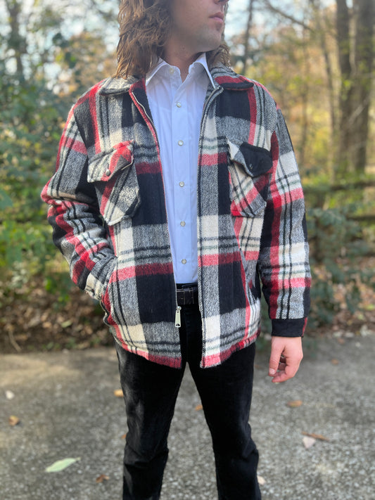 Black, red and white plaid zip front jacket with a collar and flap chest pockets, worn open by a model