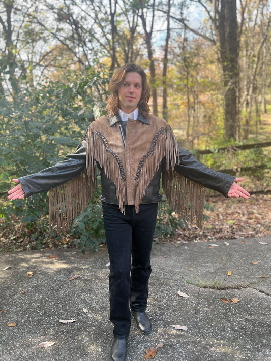 Tan and black leather motorcycle jacket with fringe and braided trim, worn by a model