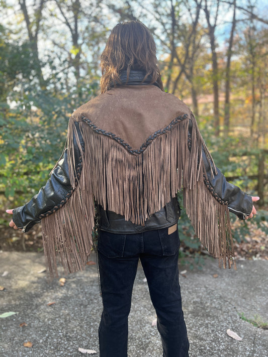 Back view on the model showing the tan suede back yoke with braided trim and fringe down the back and sleeves
