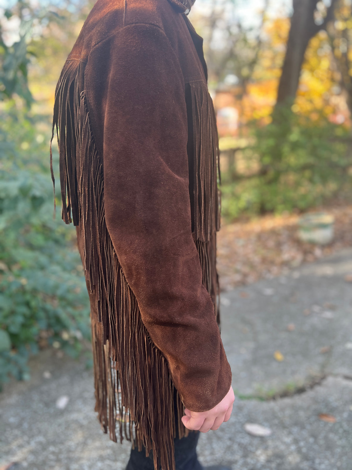 Side view on the model showing the sleeve with fringe hanging along the back of the arm and at the hem
