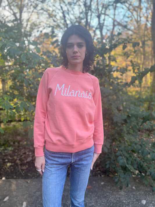 Peach sweatshirt with script 'Milanais' lettering on the chest, worn by a model