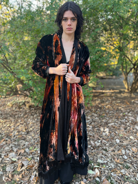 Long black crushed velvet coat with brown and orange streaks and black fringe on the collar, worn open by a model