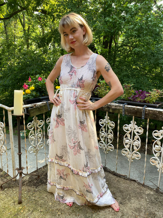 Cream sleeveless maxi dress with pink feather print and smocked bodice, worn by a model