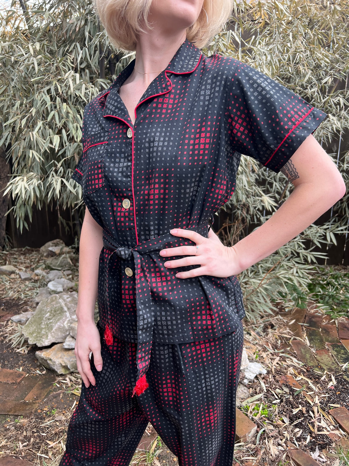 Angled view of the pajama top on the model showing the piped collar, buttons, pocket and tied belt