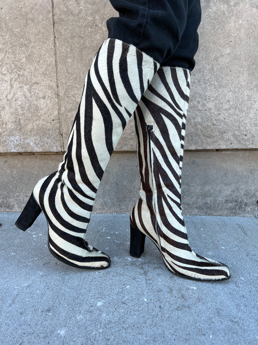 Both zebra print boots worn, angled to show the side zippers, toes and heels