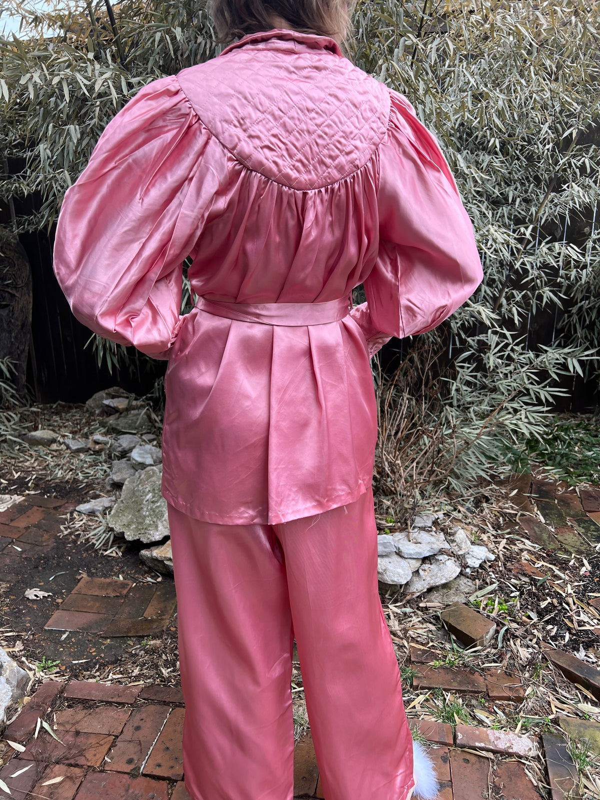 Back view of the pajama top on the model showing the quilted back yoke, bloused sleeves and belt