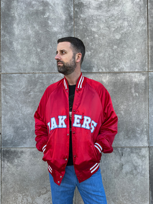 Red satin snap front baseball-style jacket with LAKERS lettering and knit collar, cuffs and hem, worn by a model