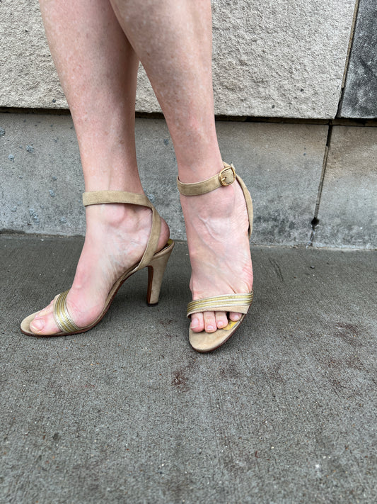 Pair of tan suede ankle strap sandals with a toe band, buckles and high heels, worn by a model