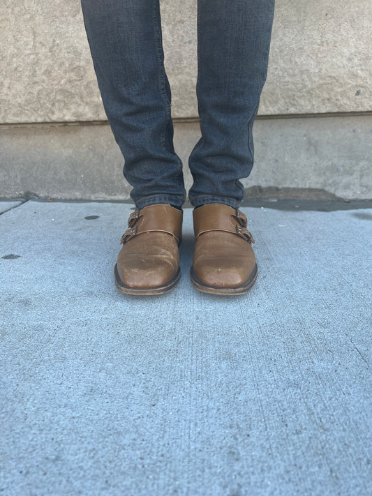 Front view of both brown buckle shoes worn with jeans, showing the toes and strap buckles