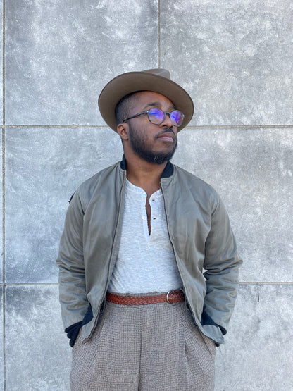 Khaki brown zip front bomber style jacket with knit collar and cuffs, worn open over a henley by a model