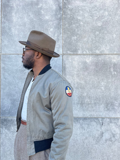 Side view on the model showing a round ROTC patch on the upper sleeve and the zip front