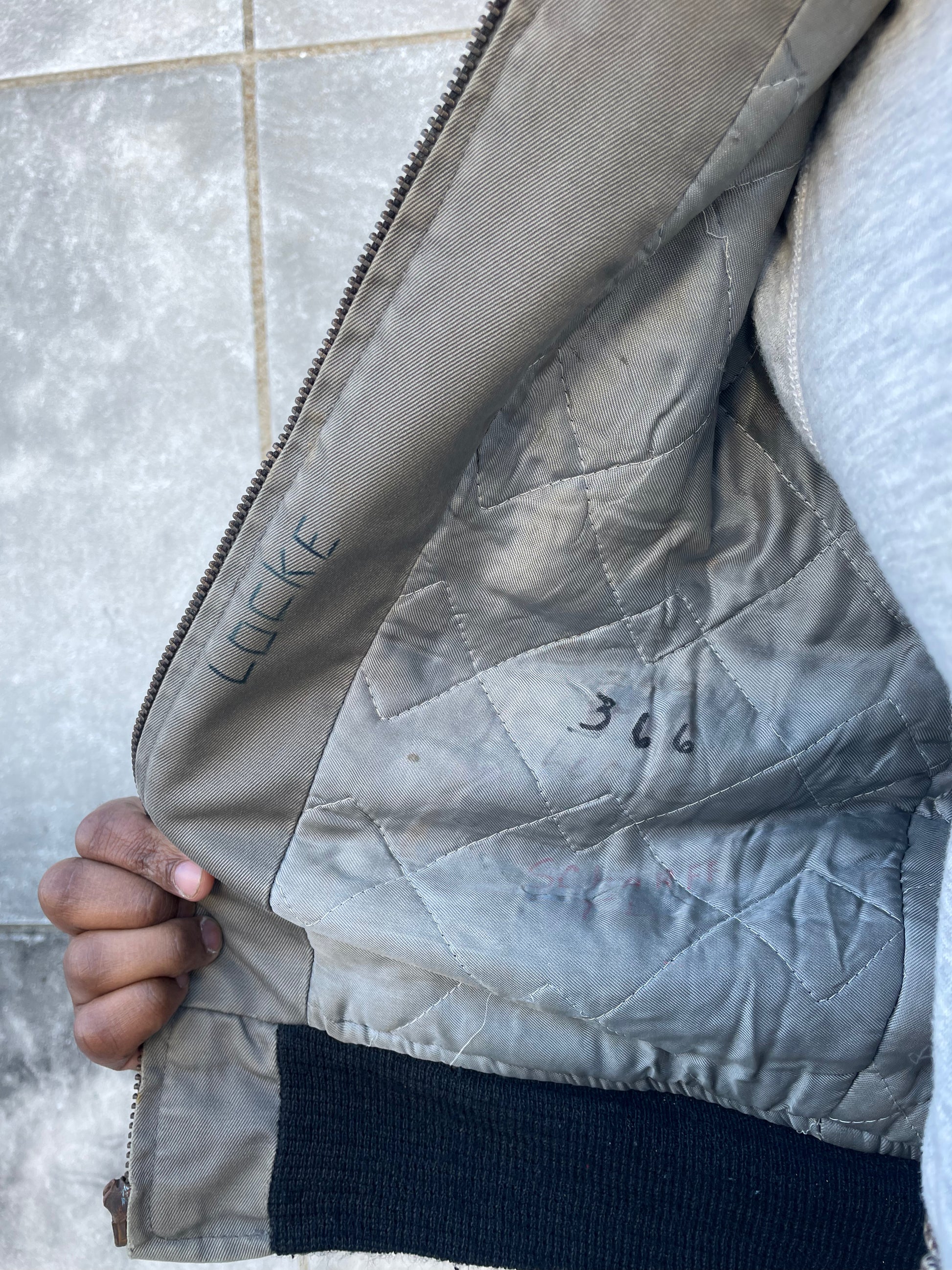 Inside of the jacket showing the quilted lining, knit waistband and handwritten ink marks
