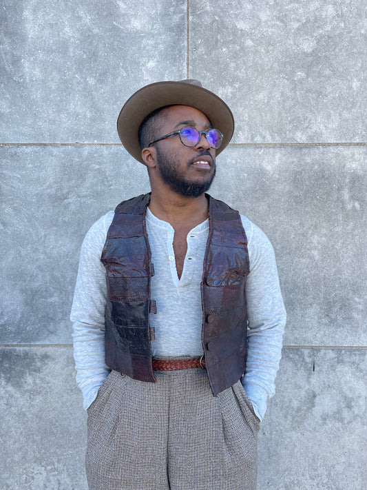 Dark brown snake skin vest with covered buttons, worn by a model