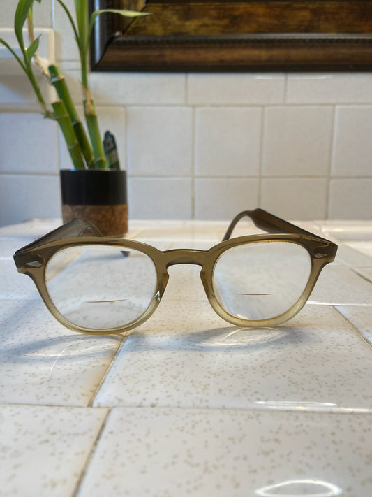 Tan and clear eyeglasses with bifocal lenses, on a tile counter