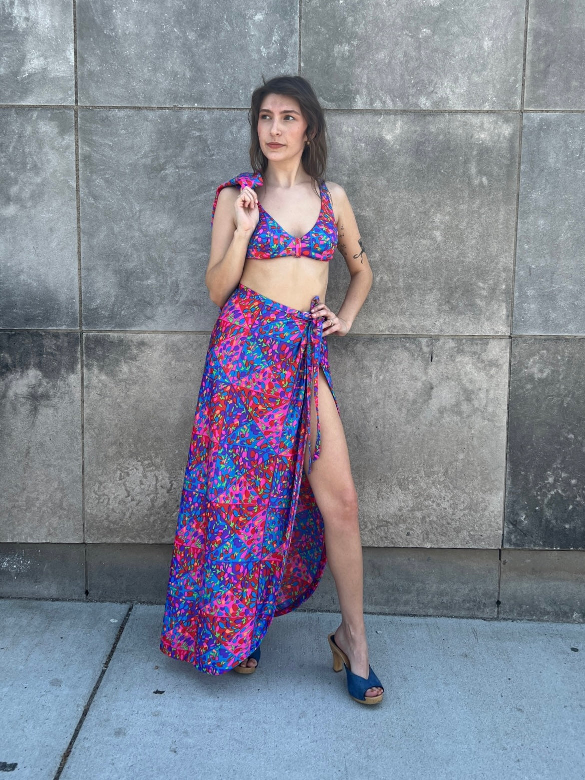 Bikini top and wrap skirt on the model, with the matching shirt hanging over one shoulder
